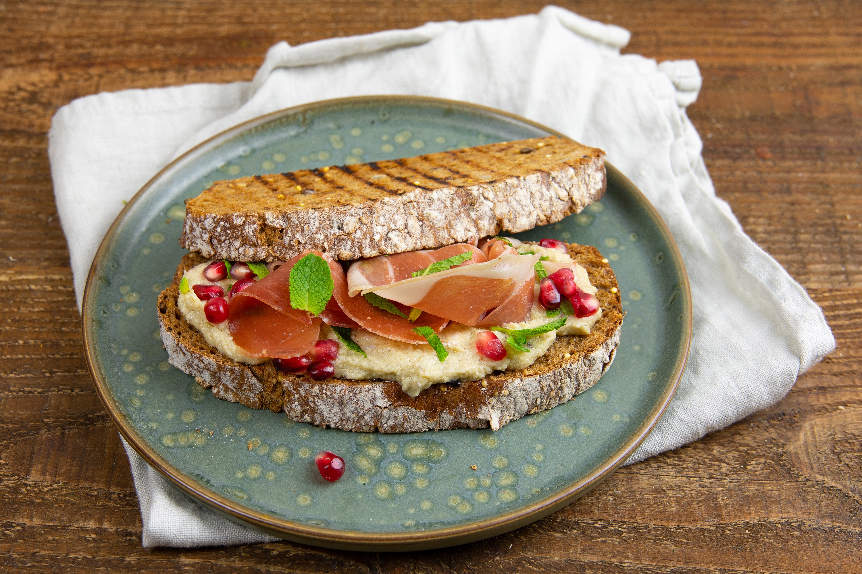 Gegrilde donkere baton met artisjokspread, serranoham & granaatappel